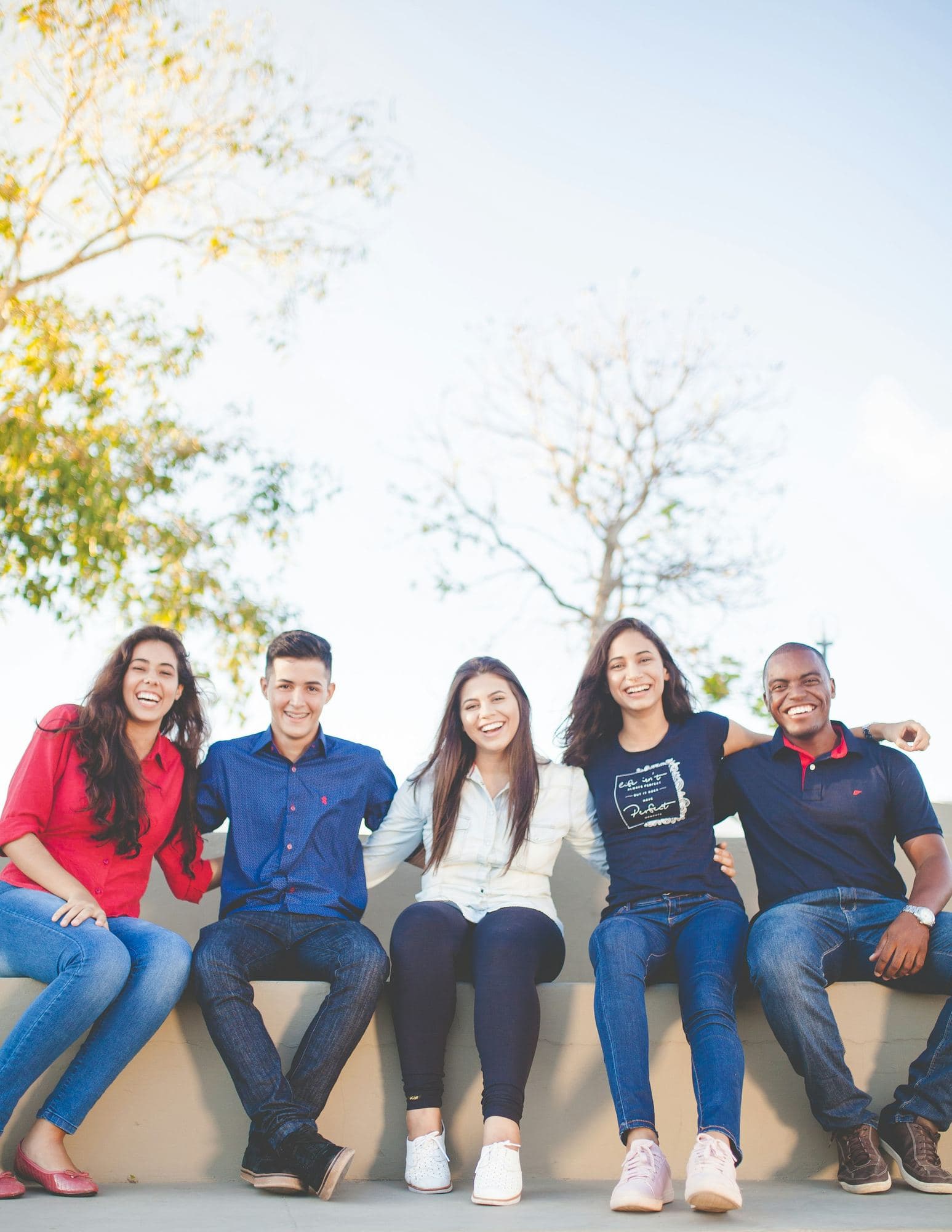 Cinq amis de cultures différentes assis côte à côte, souriants